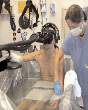 Figure 1: Burn-injured patient experiencing immersive virtual reality distraction while undergoing wound cleaning partially submerged in a hydrotank. (copyright Hunter Hoffman, University of Washington)